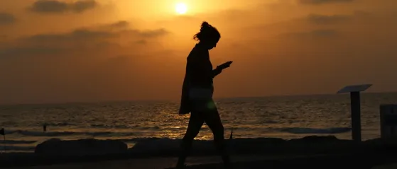 Frau die bei Sonnenuntergang am Strand spazieren geht