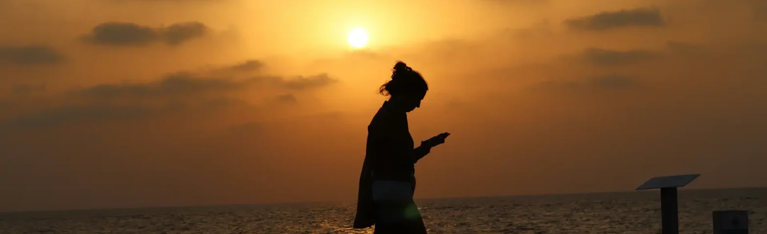 Frau die bei Sonnenuntergang am Strand spazieren geht