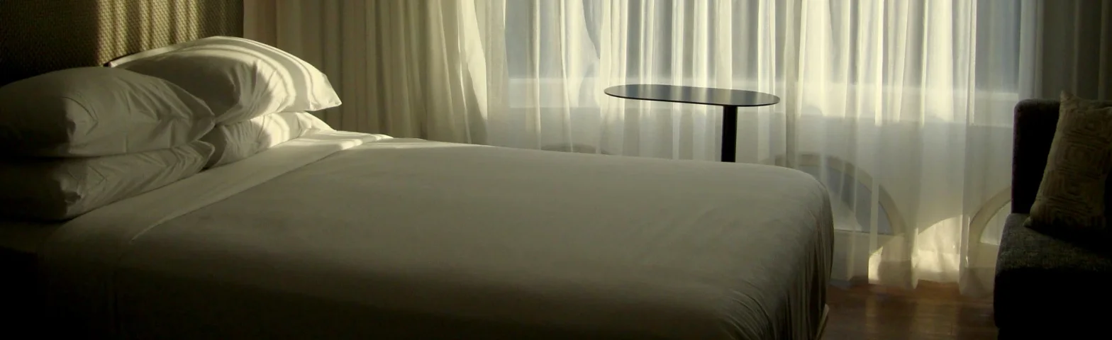 Gemachtes Bett mit transparenten Vorhängen im warmen Licht