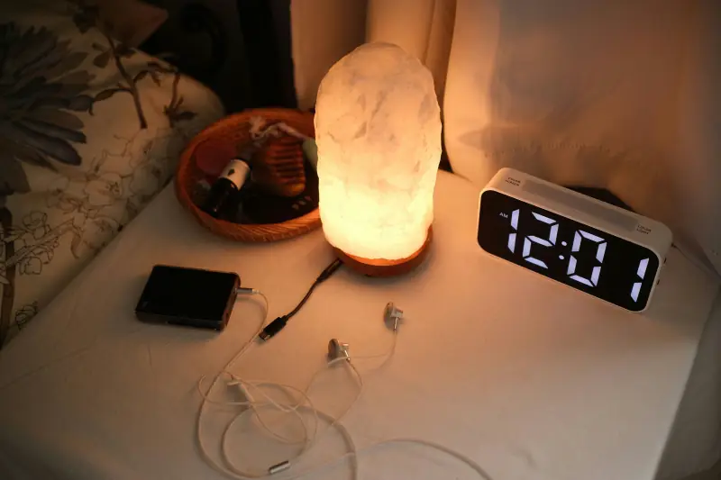 Nachttisch mit Salzkristalllampe und Wecker