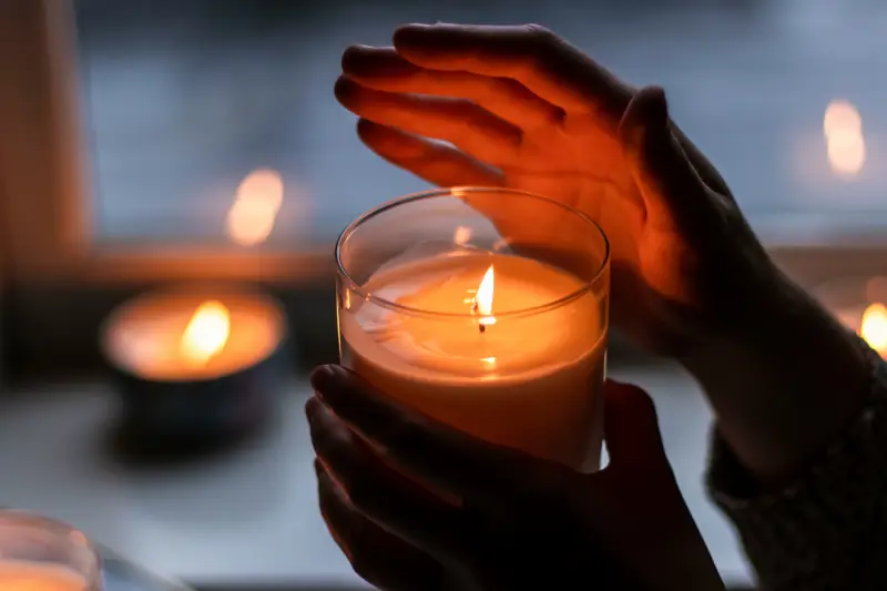 Brennende Kerze im Glas in einer Hand gehalten